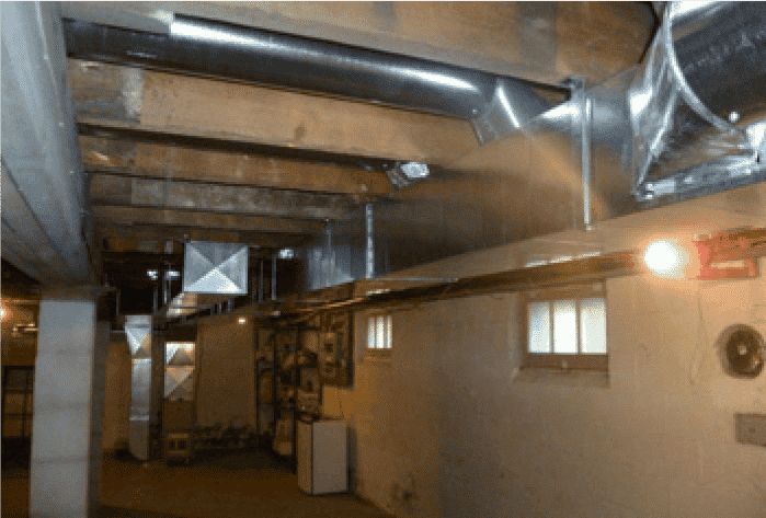 Ductwork and ventilation system installed in a basement with exposed wooden beams and metal ducts.