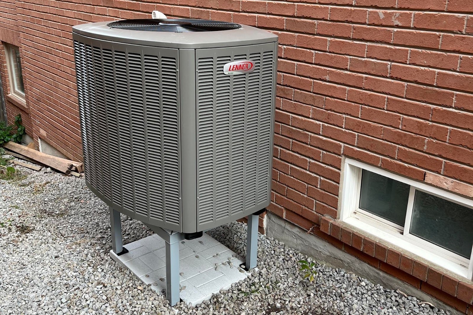 A Lennox heat pump elevated from the ground.