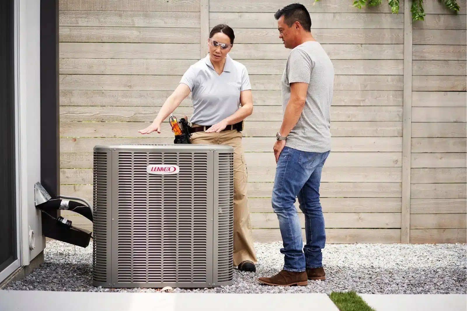 An HVAC specialist introducing an outdoor AC unit to a homeowner.