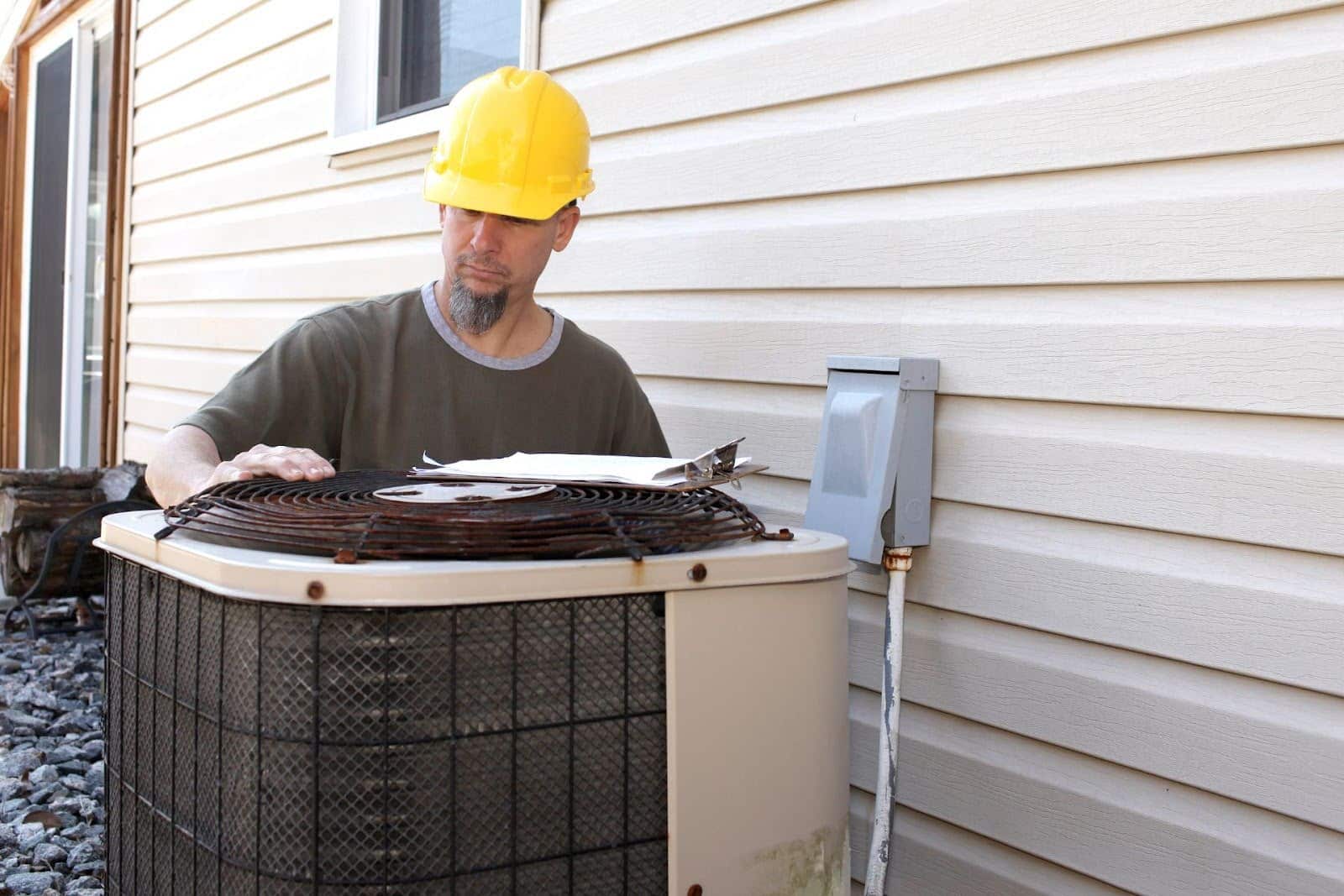 A technician is checking an old rusted AC for replacement.